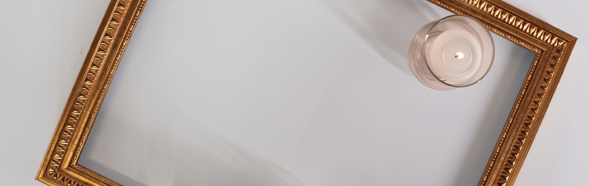 Gold gilt frame on a white background with a candle in it