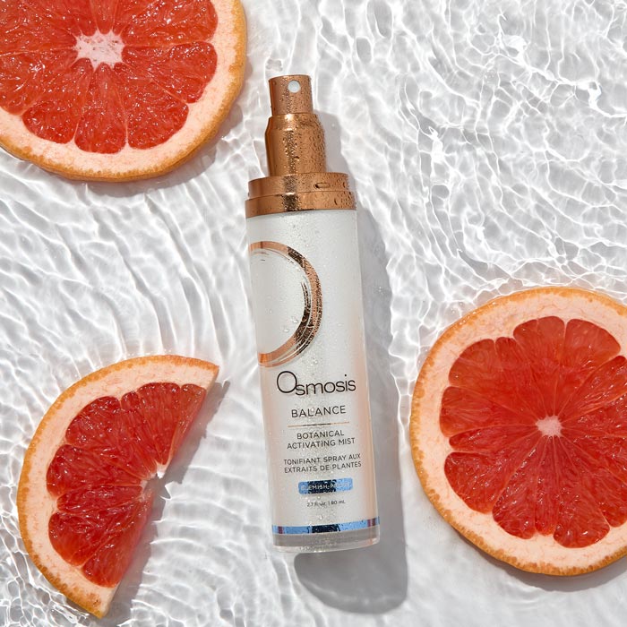 Osmosis Balance Botanical Activating Mist with sliced grapefruits on a textured white background