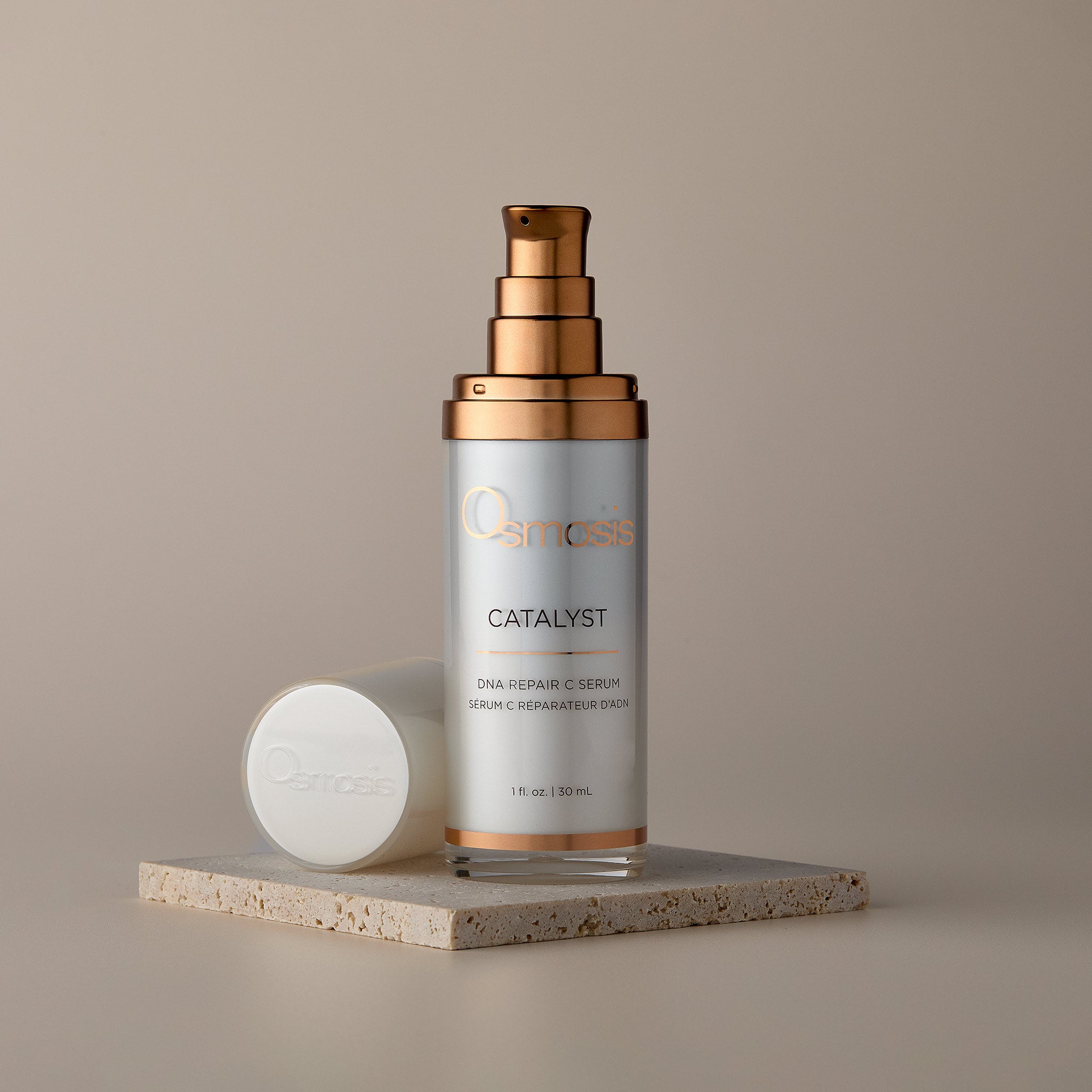 Osmosis Catalyst Serum on a stone tray with the cap removed on a tan background