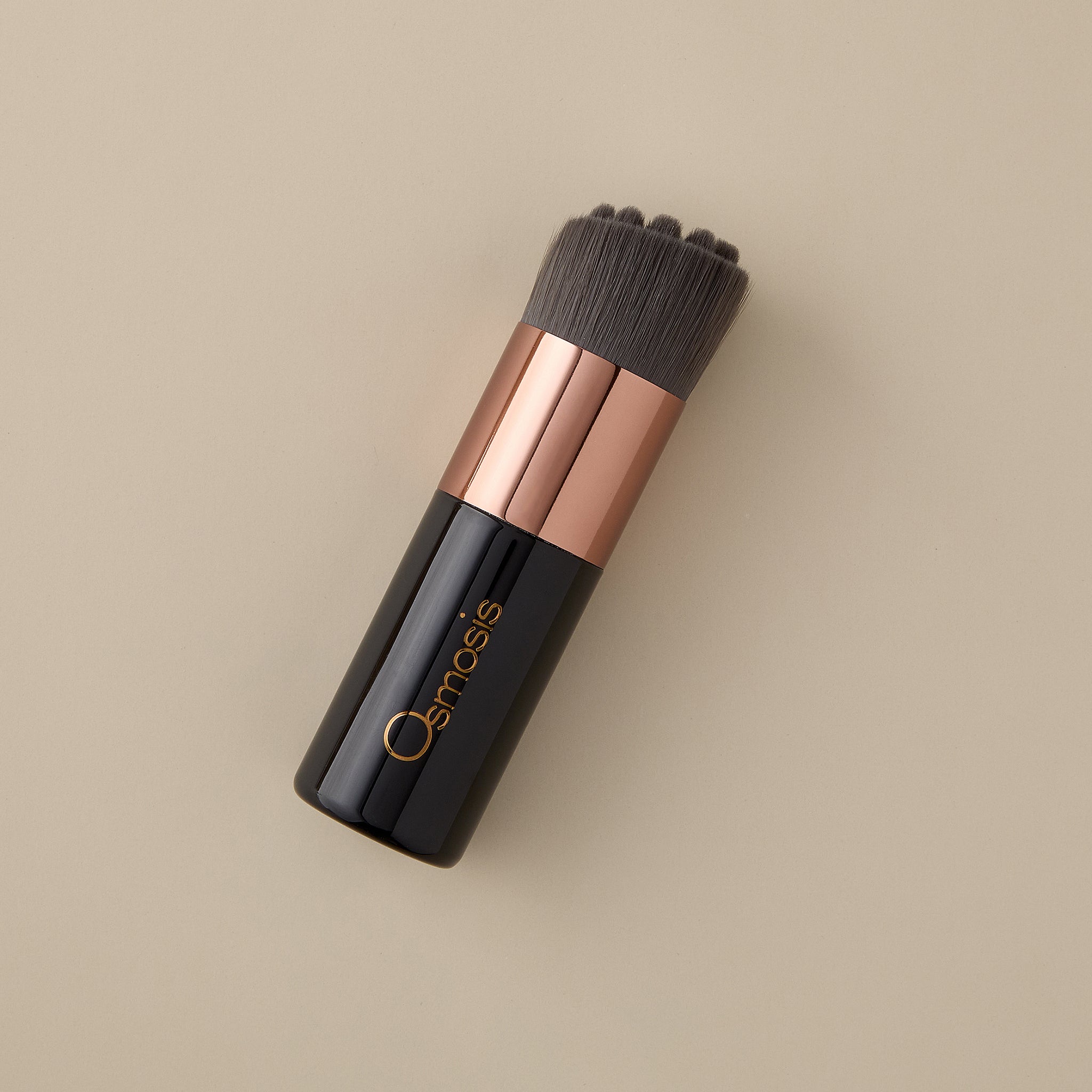 Osmosis Kabuki Skincare Brush on beige background