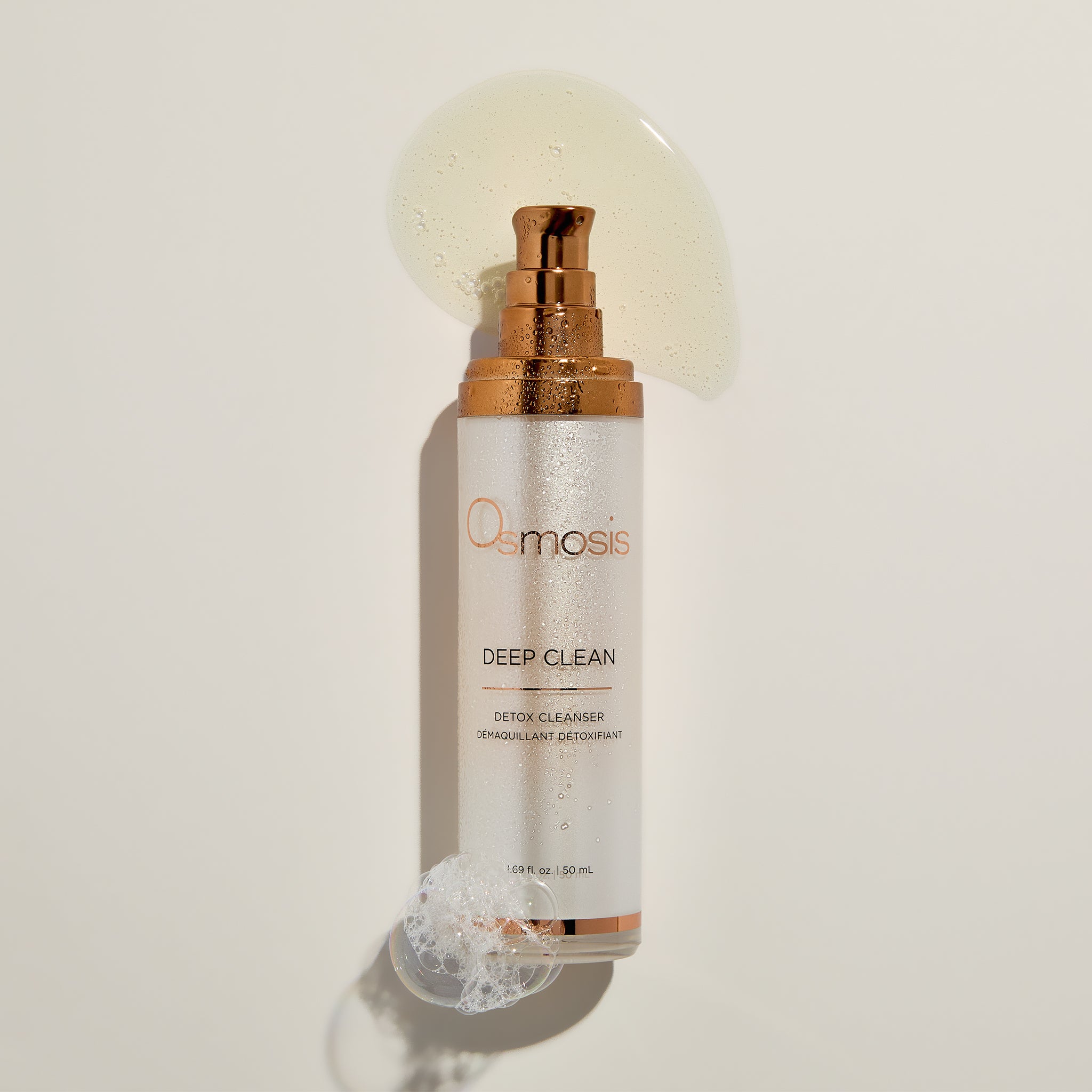 Osmosis Deep Clean Cleanser with product swatch, water mist, and bubbles on a beige background