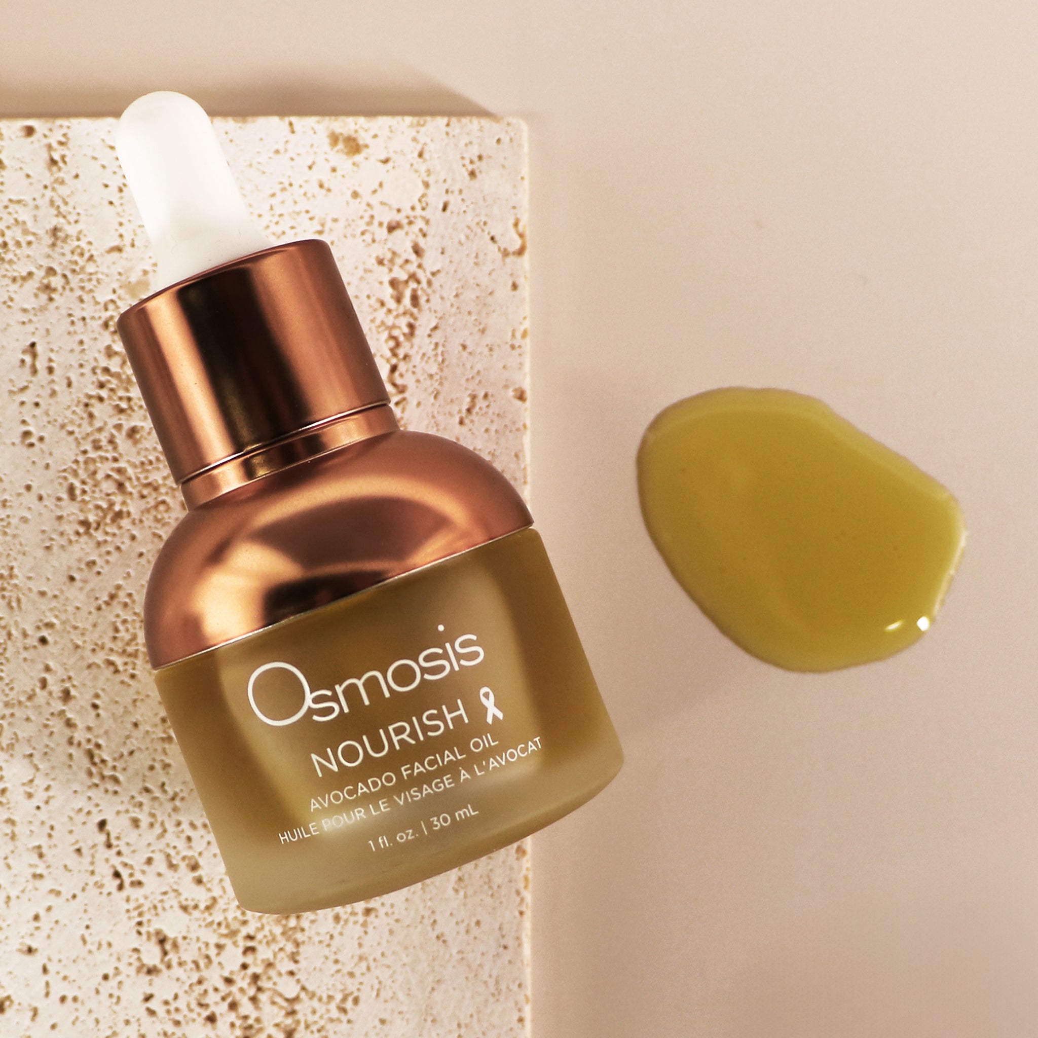 Osmosis Nourish Avocado Facial Oil with product swatch on a stone and tan background