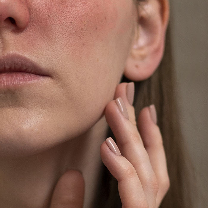 Lower quandrant of a womans face that she is touching with her hand.