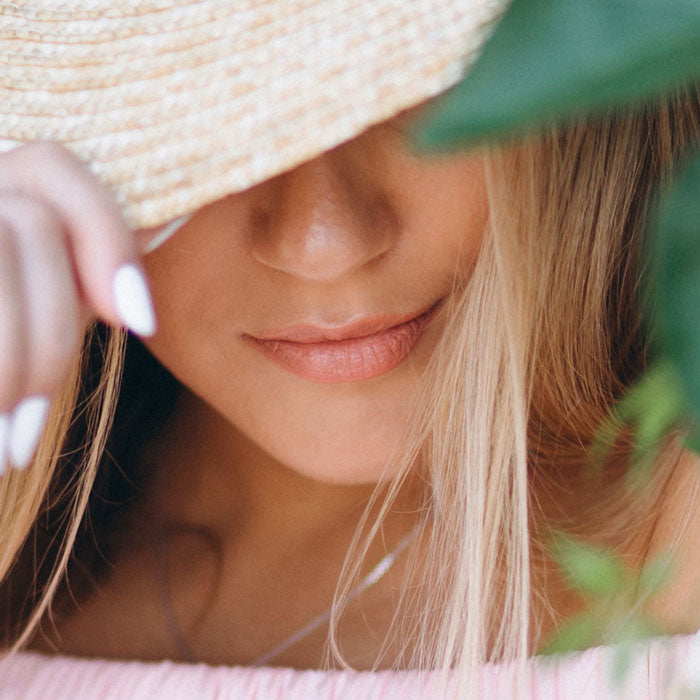 Close-up of a woman wearing a straw hat with a blurred background