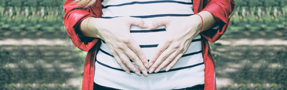 Pregnant woman with her hands in the shape of a heart on her belly, Skincare and Pregnancy from Osmosis Beauty