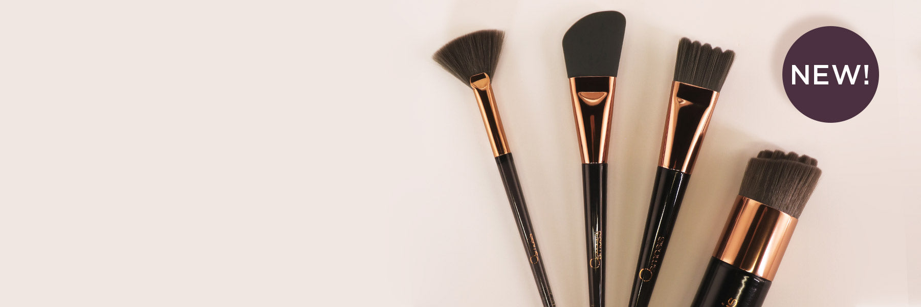Set of makeup brushes with black bristles and rose gold handles on a white background, featuring a 'NEW!' label.