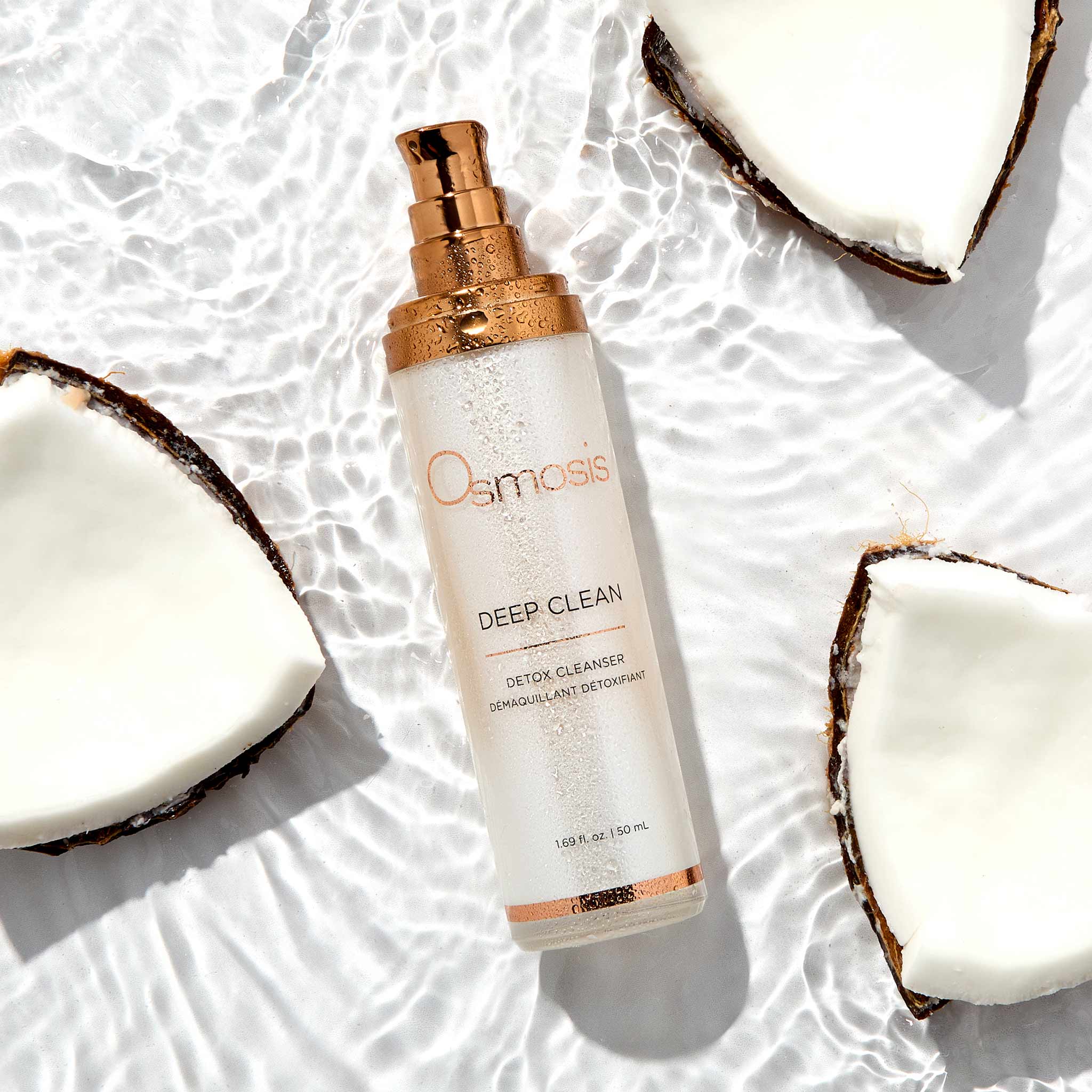 Omniasis Deep Clean detox cleanser bottle with coconut halves on a textured white background