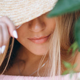 Close-up of a woman wearing a straw hat with a blurred background