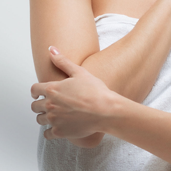 Person examining their arm with a white towel draped over their shoulder