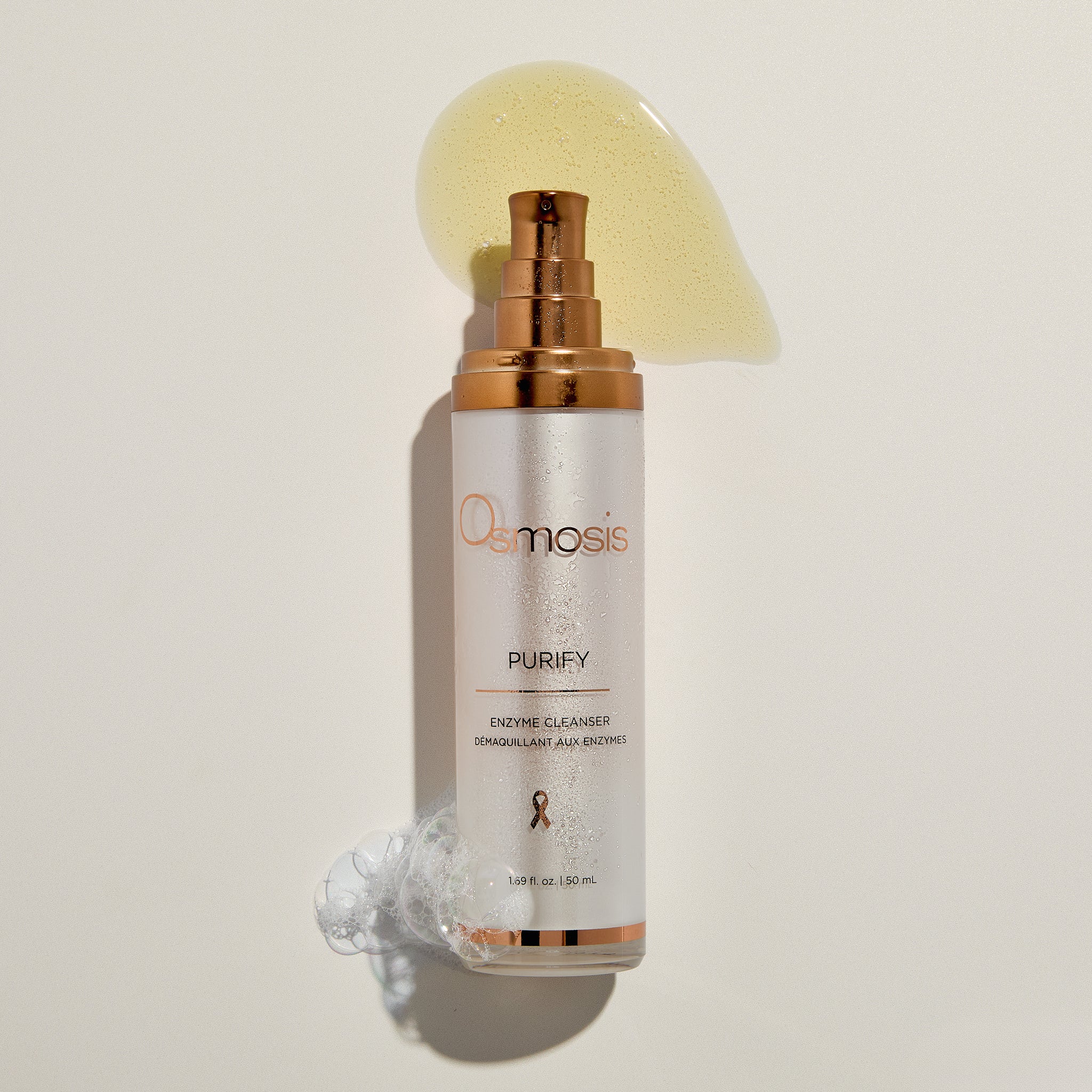 Osmosis Purify Cleanser pump with product swatch, bubbles, and water mist on a beige background