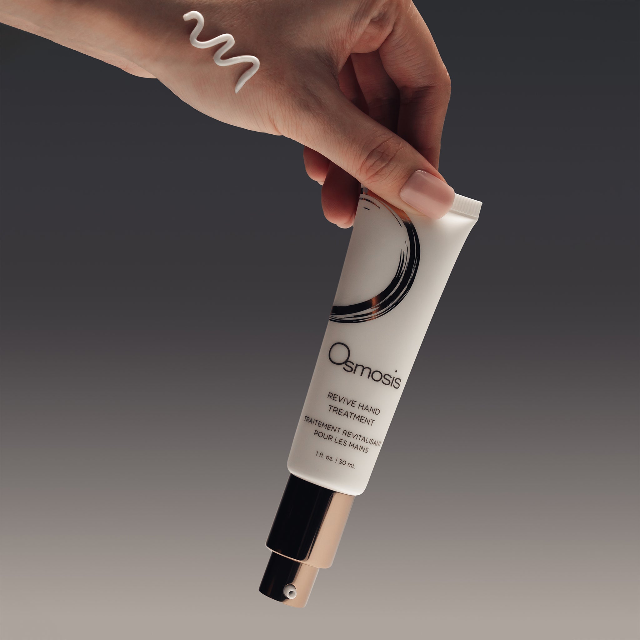 Osmosis Revive Hand Treatment being held in fingers with swatch on hand